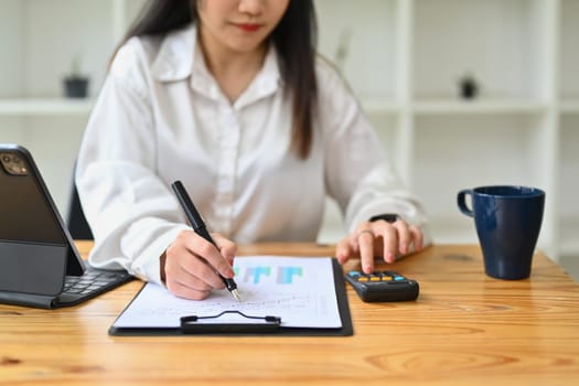 Female accountant checking report, financial data or bookkeeping at desk. Finances and economy concept.