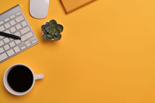 Top view of coffee cup, keyboard and notebook on yellow background. Space for text advertising text message.