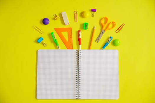 Notebook on a spring for notes and stationery lie on a yellow background, the concept of back to school, colorful school supplies