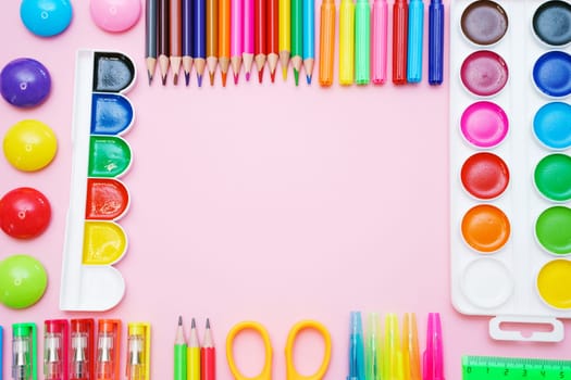 School supplies, colored pencils, watercolor paints, pens, ruler and scissors on a pink gentle background. Back to school creative, mockup concept.