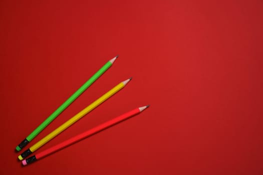 Colored wooden pencils on red background, education concept