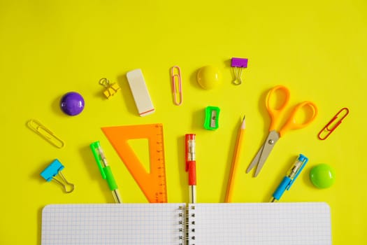 Notebook on a spring for notes and stationery lie on a yellow background, the concept of back to school, colorful school supplies