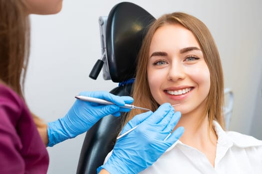 Portrait of young smiling woman sitting in the dental chair before teeth treatment in stomatology office