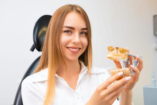 Portrait of young woman patient holding a model jaw.