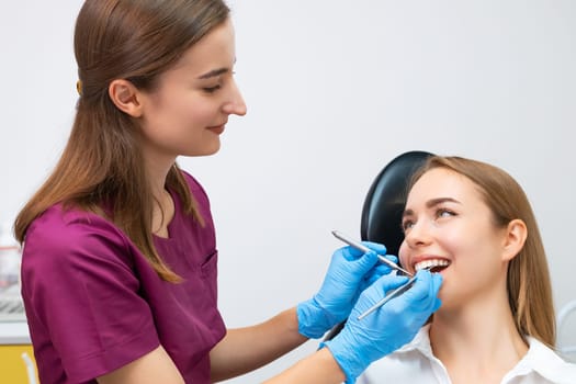 Dental treatment is being administered by the dentist to a female patient with a perfect smile