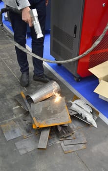 Laser metal cleaning. A man using laser metal cleaning machine to clean a metal surface from rust. Worker cleaning metal from coating by laser. Steel laser clean technologies. New modern technology