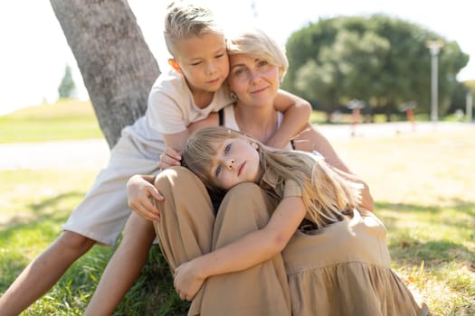 Mother and kids relaxing under a tree in a sunny park