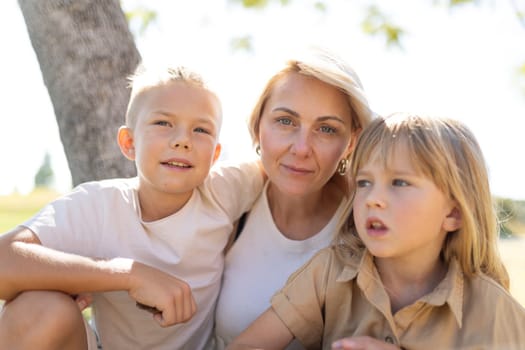 Mother and two children sitting together under a tree
