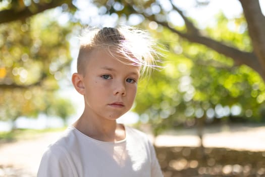 Boy standing in sunlight with trees in the background