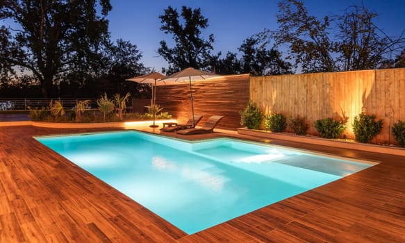Elegant swimming pool with warm lighting and natural wooden deck