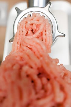 Close-up of pink minced turkey comes out of a metal meat grinder. The concept of dietary recipes, proper and healthy nutrition, the cooking process. High quality photo