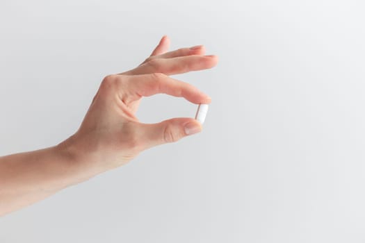 Female taking medicine, holding white pill and a glass of water on white background. Concept of health care, dietary supplements, treatment of depression and diseases. High-quality photo