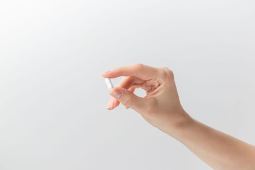 Female taking medicine, holding white pill and a glass of water on white background. Concept of health care, dietary supplements, treatment of depression and diseases. High-quality photo