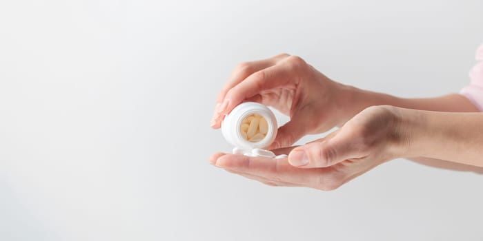 Female taking medicine, holding white pill and a glass of water on white background. Concept of health care, dietary supplements, treatment of depression and diseases. High-quality photo
