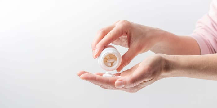 Female taking medicine, holding white pill and a glass of water on white background. Concept of health care, dietary supplements, treatment of depression and diseases. High-quality photo