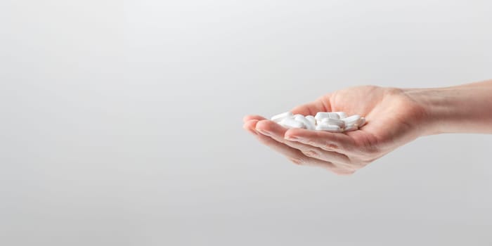 Female taking medicine, holding white pill and a glass of water on white background. Concept of health care, dietary supplements, treatment of depression and diseases. High-quality photo