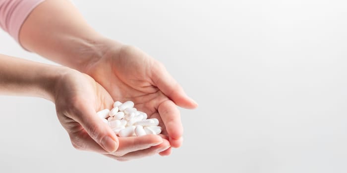 Female taking medicine, holding white pill and a glass of water on white background. Concept of health care, dietary supplements, treatment of depression and diseases. High-quality photo
