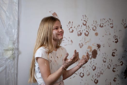 A young girl is joyfully demonstrating her vibrant creativity through the use of paint and colorful handprints