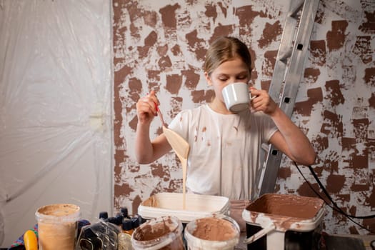 A young individual delights in a DIY project while sipping coffee in an inspiringly textured renovation workspace