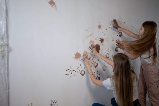 Two enthusiastic individuals are engaged in a creative wall art project using vibrant paint to express themselves