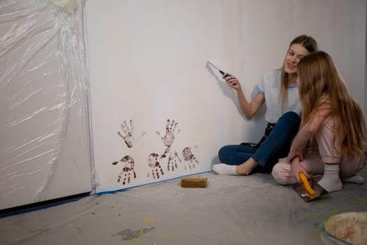 Two joyful girls enthusiastically renovate their lovely home, collaboratively painting and decorating the wall together