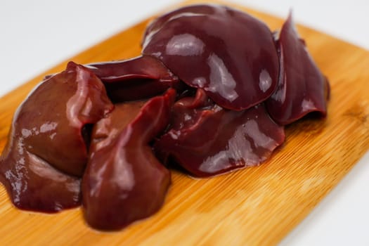 Close-up of raw chicken liver on a wooden board on a white background. The concept of healthy eating, cooking. High quality photo