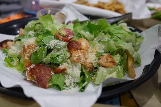 Caesar Salad. A plate of classic Caesar salad, featuring romaine lettuce, croutons, Parmesan cheese, and Caesar dressing, perfect for salad menus