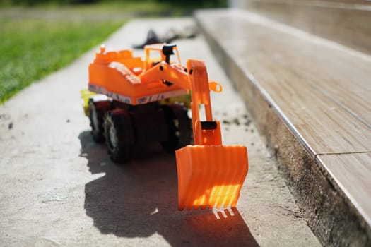 A yellow backhoe toy left behind after playing.