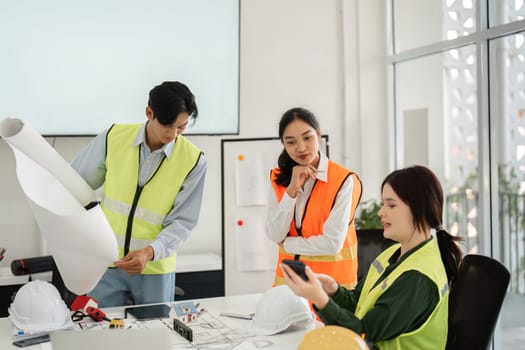 A diverse construction team reviewing architectural blueprints and discussing project updates, demonstrating effective communication in a sleek modern office environment.