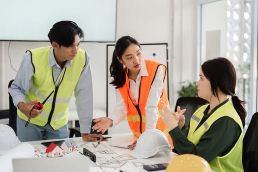 A diverse construction team actively engaged in a detailed discussion about building plans, showcasing collaboration and communication in a bright modern office environment.