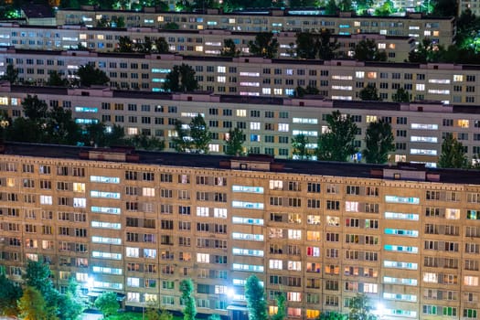 Warm lights shining from apartment windows at night, creating a cozy and inviting atmosphere in a residential area