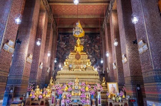 In a peaceful temple, a magnificent golden Buddha statue is surrounded by vibrant, colorful flowers