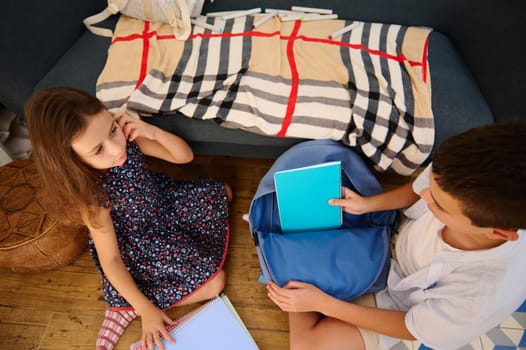 Two children engage in organizing school supplies, reflecting on education and creativity in a cozy home setting.