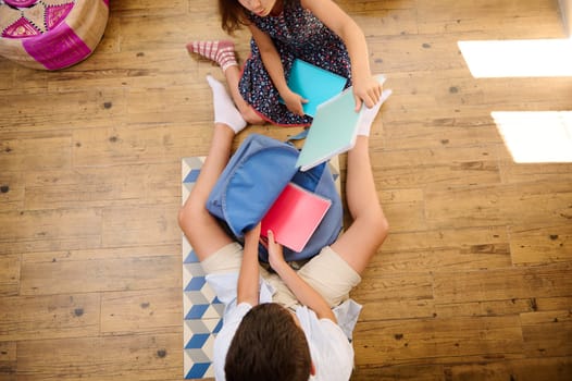 Two children organizing and preparing school supplies in a relaxed home environment, highlighting preparation and teamwork.