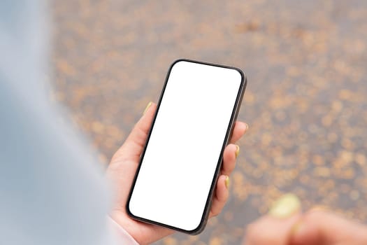 A person holds a smartphone with a blank screen capturing a moment in an outdoor urban environment.
