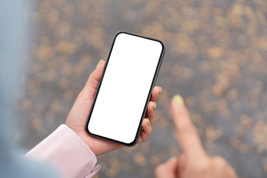 A person points at a blank smartphone screen showcasing digital interaction in an urban outdoor environment.