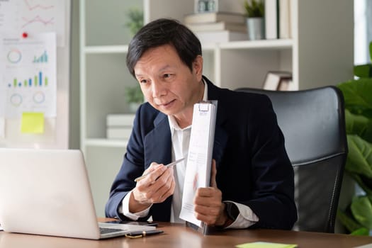 An elderly businessman focuses on market analysis embodying wisdom and experience in a modern office setting.