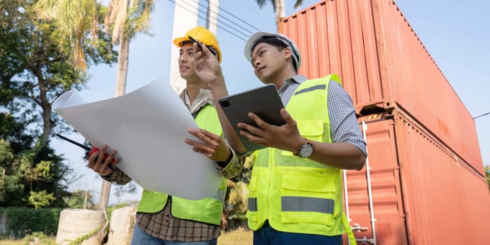 Two logistics engineers discuss container management strategies on a construction site ensuring project efficiency and safety.