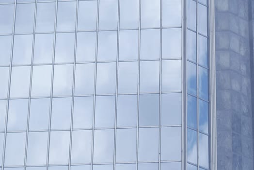 Glass windows reflect clouds in a modern urban environment.