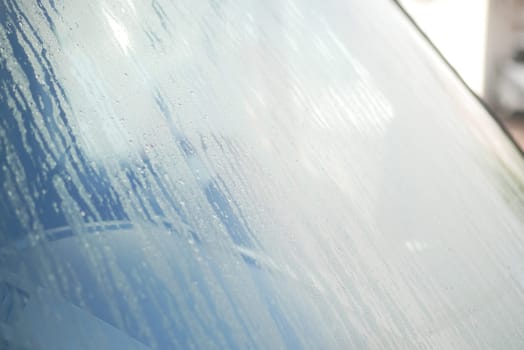 Water droplets cling to a car windshield on a chilly morning.