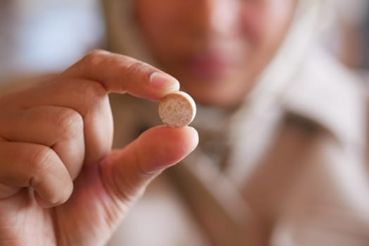 A woman displays a small round tablet with her finger in focus.