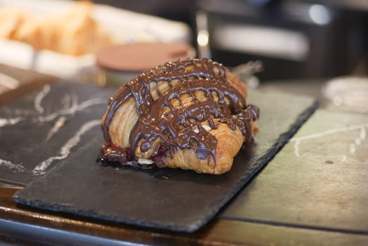 Freshly baked croissant with rich chocolate topping on display at cafe.