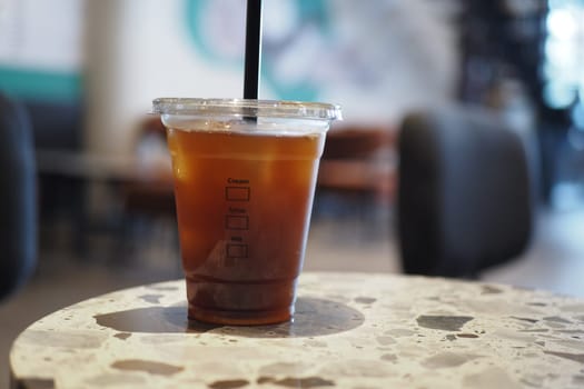 A refreshing cold brew coffee sits on a marble table in a cafe.