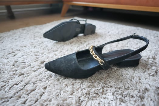 Two pairs of black slingback shoes rest on a soft, textured carpet.