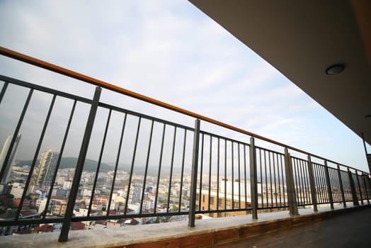 Balcony railing frames a panoramic view of a bustling city skyline.