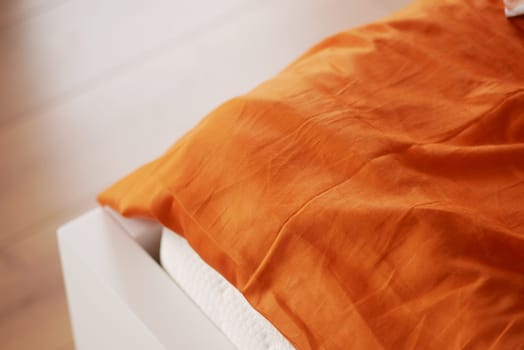 An inviting bedroom showcases a bright orange linen blanket draped over a bed.