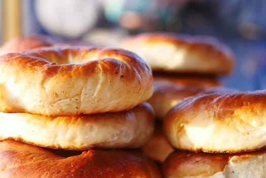 Warm, golden bagels stacked high at a bustling bakery in the morning.