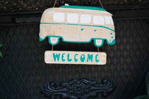 A colorful wooden sign features a vintage camper van design, welcoming visitors.