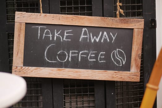 A chalkboard sign announces takeaway coffee options at a cafe.