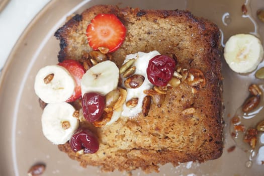 Moist banana bread served with strawberries, banana slices, and nuts